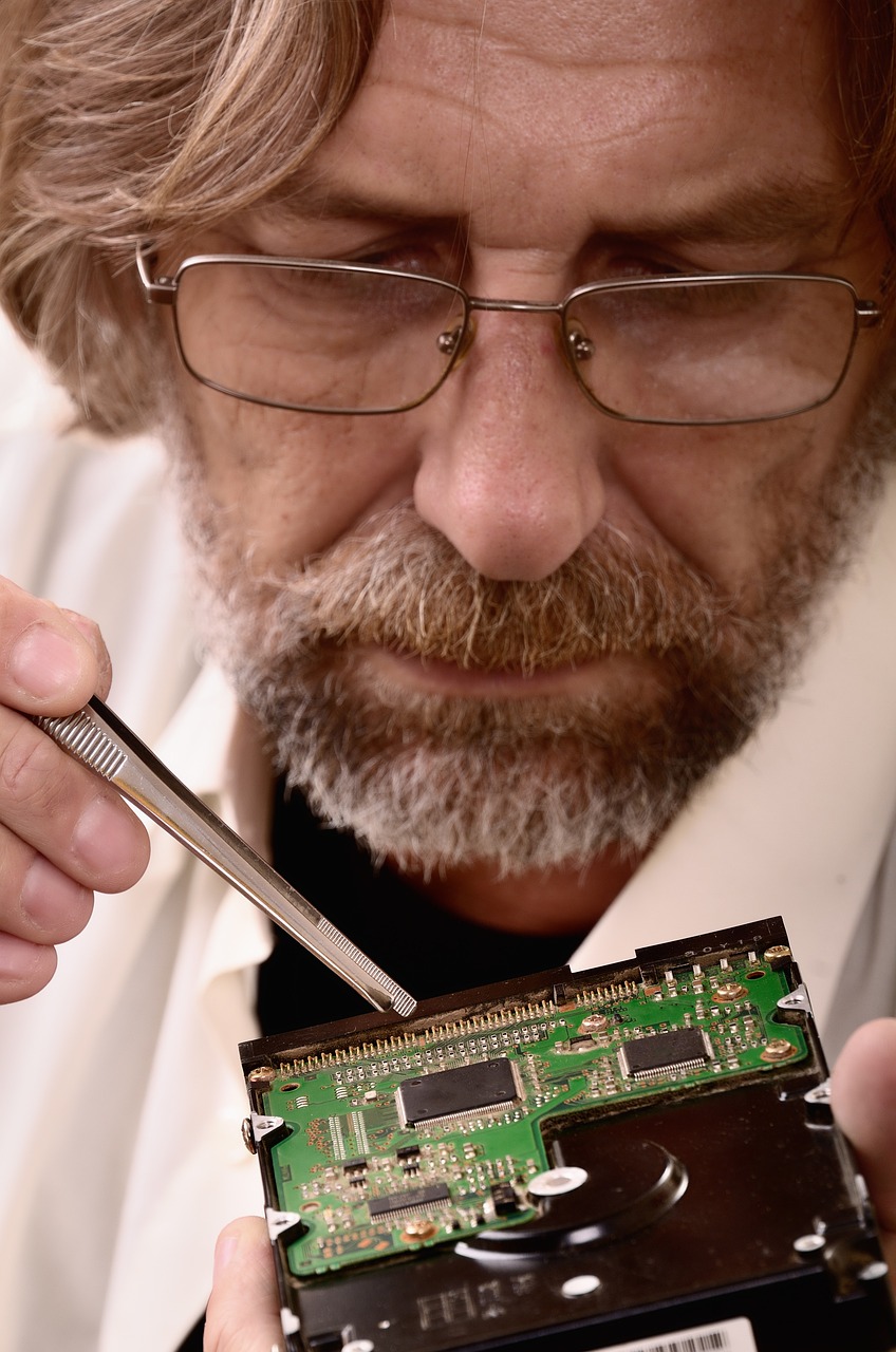 Man working on circuitry board with tweezers