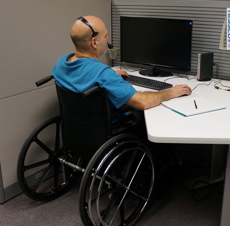 A person in a wheelchair sitting at a desk