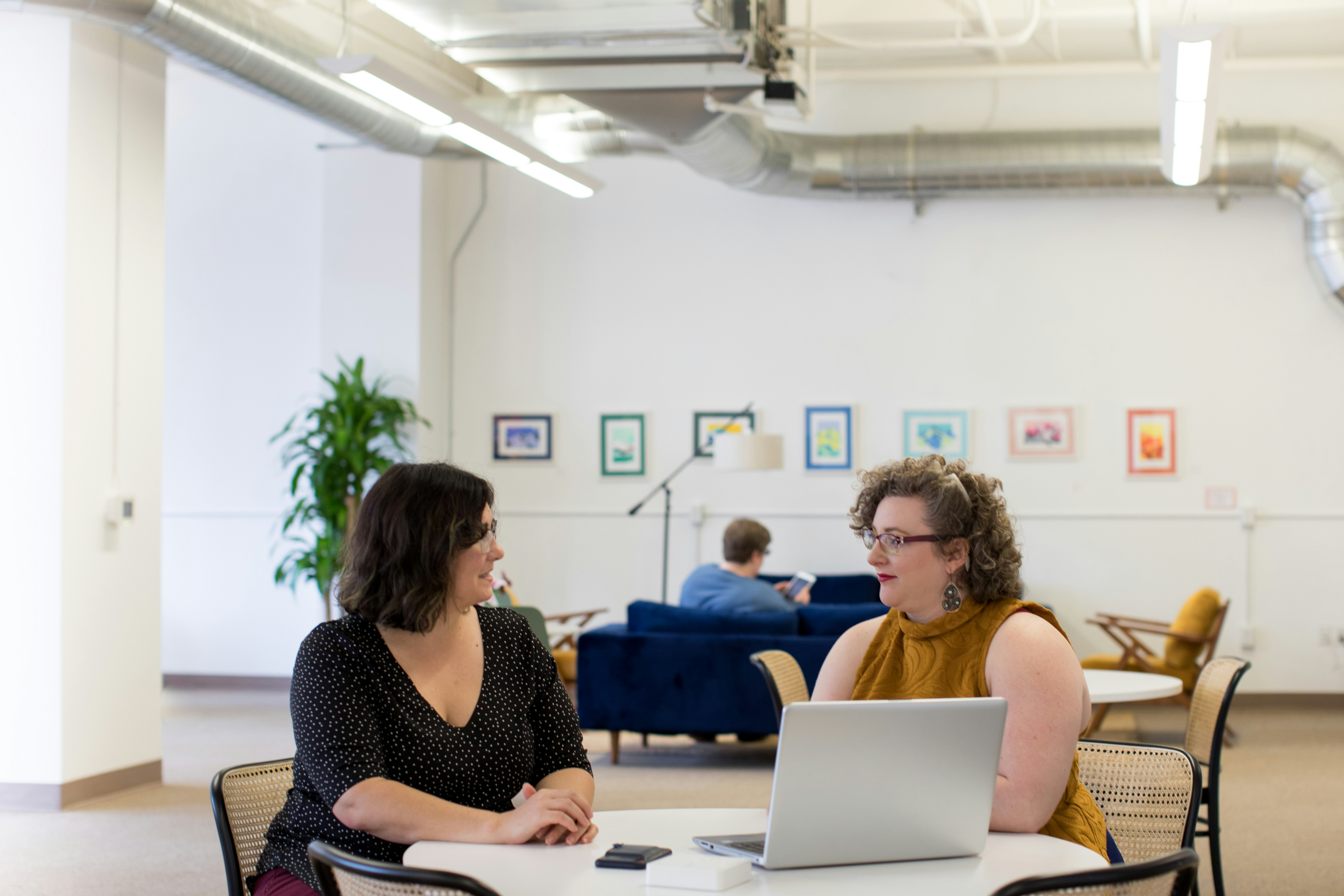 Two plus size women in an office talking over a laptop